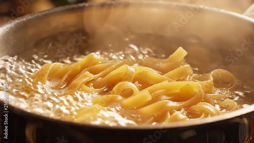 Delicious pasta cooking in boiling water in a metal pot.