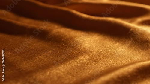 Close up of golden fabric with soft folds and light reflections.