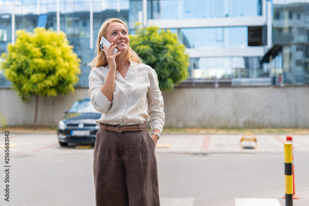 Fototapeta premium Mature woman talking on cell phone outdoors smiling