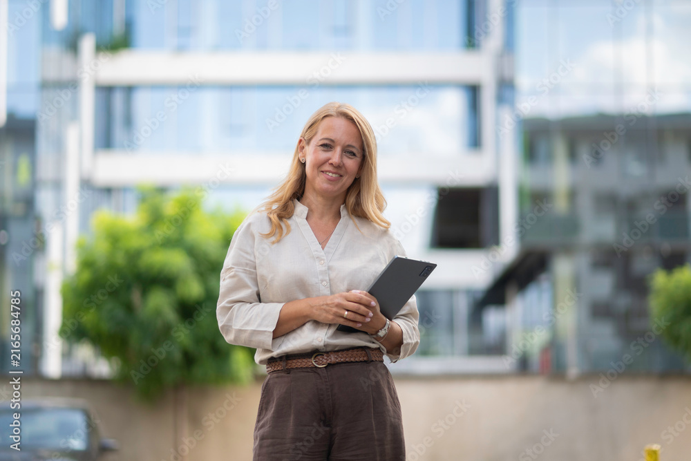 Fototapeta premium Businesswoman holding digital tablet standing in city street