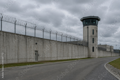 Modern correctional facility exterior with concrete wall and guard tower, security concept