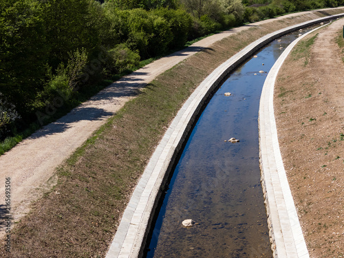 Canvastavla Aerial view of flood prevention efforts with a water channel and raised embankment near a green area