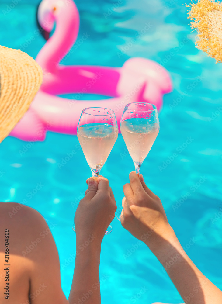 Obraz premium Women holding champagne by the pool. Selective focus.