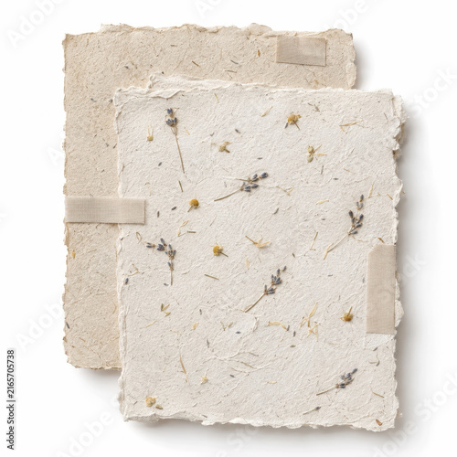 Stack of handmade paper sheets with dried leaves and tape on white background