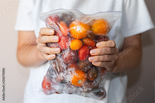 Bild auf Leinwand Hands holding a sealable bag full of frozen cherry tomatoes for food preservatio