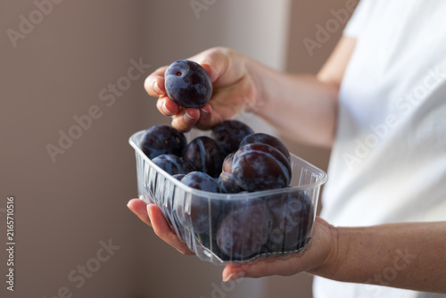 Foto Fresh ripe plums in clear plastic punnet held in hands for food background and h