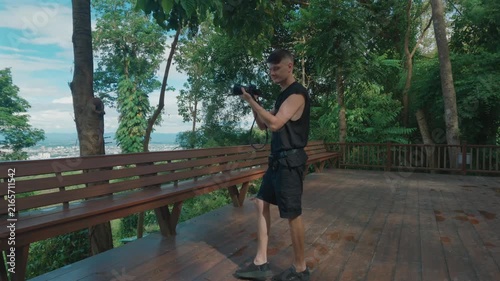 Male photographer filming with mirrorless camera at forest viewpoint in Chiang Mai, Travel videographer recording nature scenery with camera in Thailand 4k