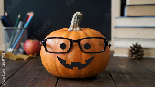 Halloween pumpkin with glasses and smile carved on wooden table for festive decoration