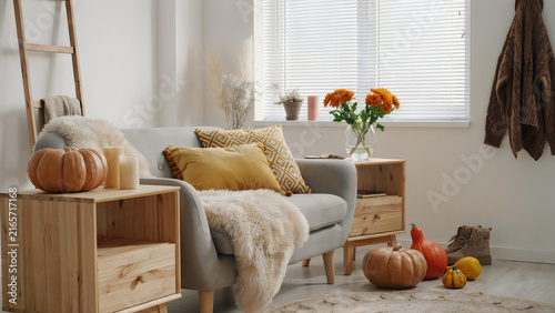 Cozy autumn living room with Halloween pumpkins and warm knitted blanket on sofa