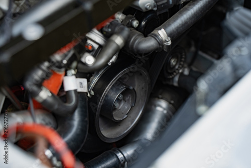Serpentine belt and pulley system inside a high performance vehicle engine bay showing mechanical components and routing