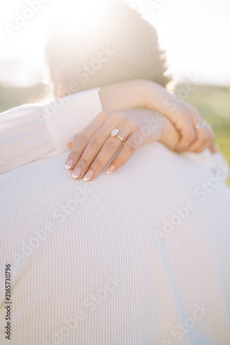 Картината върху платно Sunlit close-up of pear-shaped diamond engagement ring embrace