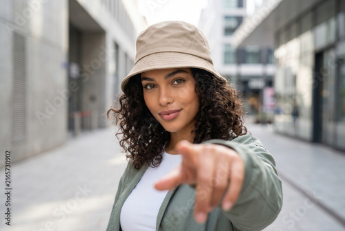Confident Woman Pointing at Viewer on Modern City Street