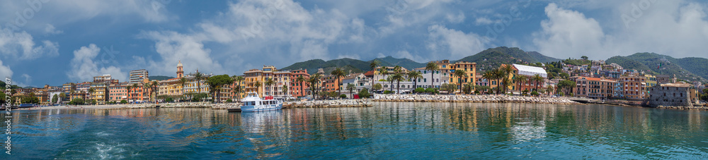Obraz premium Panoramic view with the famous promenade and the harbor of the city of Rapallo, on the Golfo del Tigullio, Liguria region, Italy. Colorful Ligurian-style buildings, palm trees, views of the calm sea.