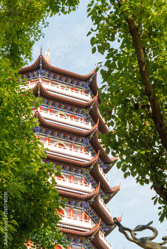 Fotografía Traditional Pagoda Tower Framed by Lush Green Trees