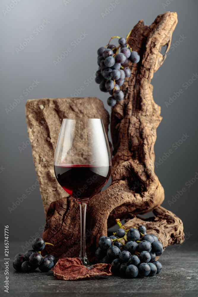 Fototapeta premium Red wine with stone, dried snags, and blue grapes.