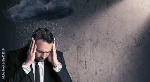 Stressed businessman in suit under rain cloud representing professional burnout and pressure