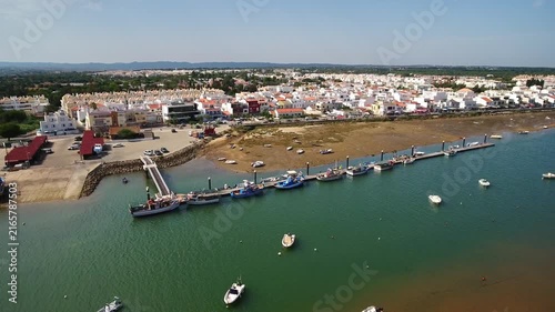 Beautiful aerial footage showing the picturesque fishing village of cabanas de tavira in the sunny algarve region of portugal, featuring its charming harbor and boats on the ria formosa lagoon