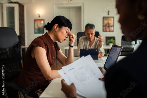 Stressed businesswoman with coworkers in office meeting