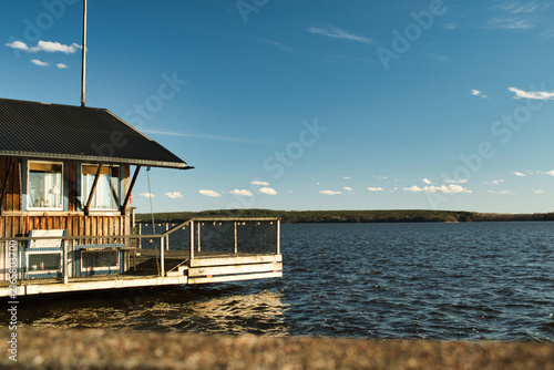 Fotografía Wooden lake house with dock on calm blue water, Sweden