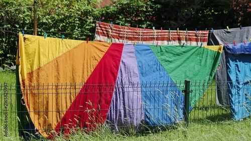 Washed bed linen is hung on a clothesline outside. The washed items are swaying in the wind.