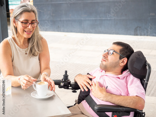 Foto Caregiver woman and man with disability having coffee and conversation at an out