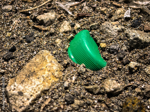 Konstfotografi Green Plastic Waste Fragment Lying on Dry Sandy Ground Representing Environmenta