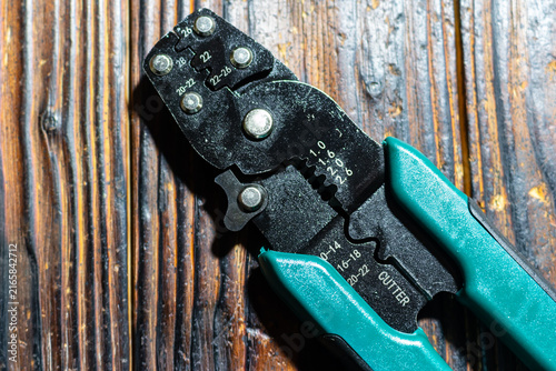 Obraz na płótnie Professional heavy duty wire crimping tool with green handles placed on a rustic
