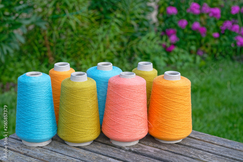 Large spools of colored industrial thread organized in rows
