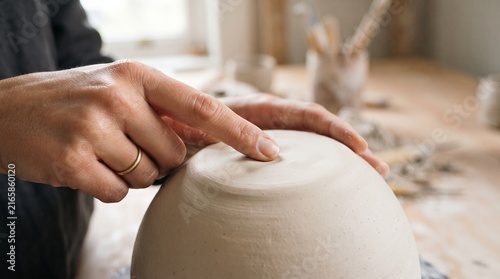 Hands shaping a clay bowl on a potter's wheel, capturing the delicate artistry and craftsmanship involved in pottery.