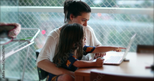 Candid authentic mother daughter child together in front of computer screen browsing the internet