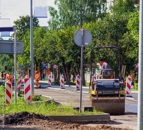 Canvastavla Road roller compacting ground at city street construction site with warning barr