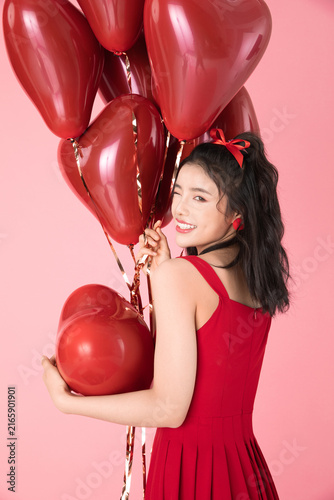 Foto Smiling young woman with red heart balloons on pink background