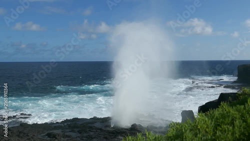 Blowhole spouting large plumes of water on Galapagos Islands with veil of mist and churning ocean waves