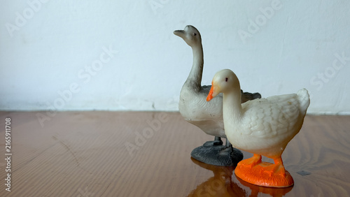 Obraz na płótnie Two duck figurines standing together on a smooth table surface, animal decor, domestic pair, simple statuette