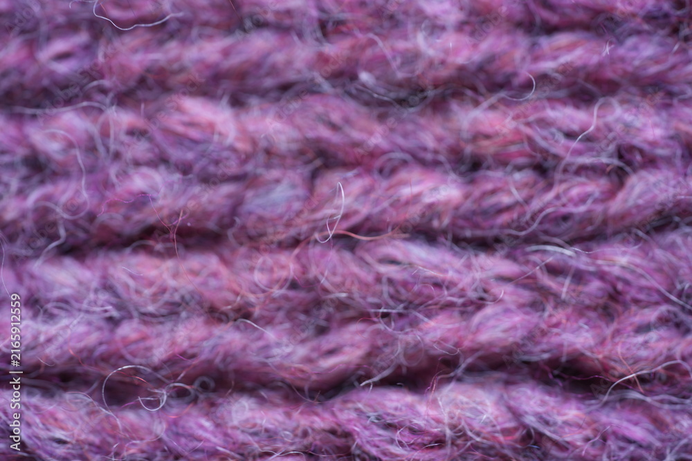 Obraz premium Purple wool knit texture background Macro close-up of purple knitted wool fabric with soft fuzzy yarn and visible stitch pattern. Cozy warm textile texture in rich violet tones, ideal for fashion, win