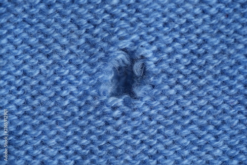 Fotografía hole in a light blue woollen jumper, hole in a blue woollen jumper, texture of a