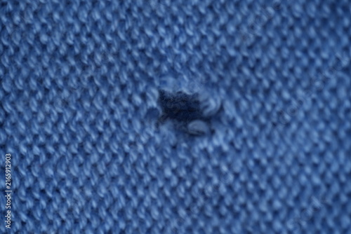 Bild auf Leinwand hole in a light blue woollen jumper, hole in a blue woollen jumper, texture of a