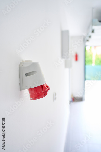 Red industrial electrical socket is mounted on wall inside garage