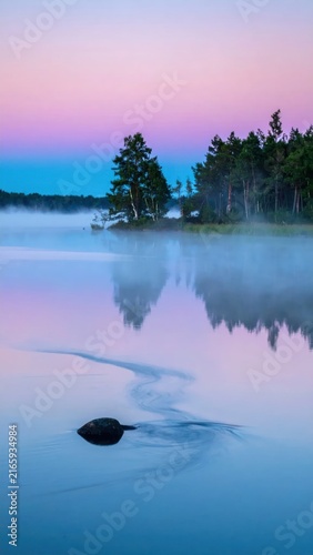 Colorful sunset sky reflecting in misty lake water.