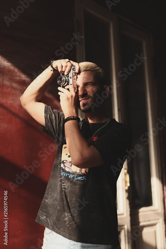 Photography Caucasian male with casual attire adjusting retro camera outdoors