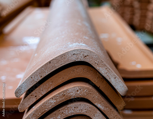 stacked terracotta ceramic ridge tiles and curved roof capping elements