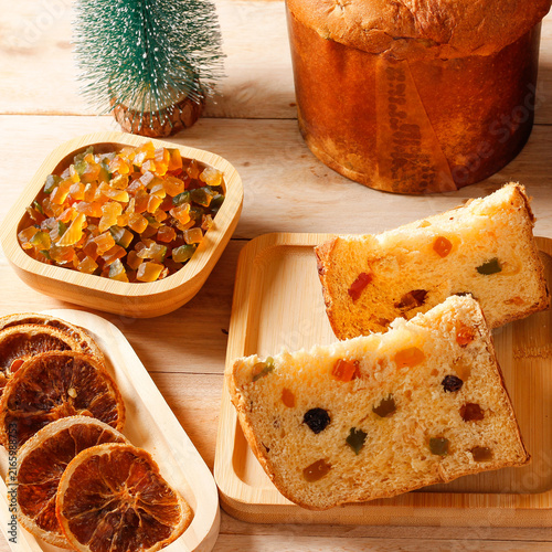 Slices of Christmas panettone with candied fruit and raisins on a bamboo tray, in a rustic Christmas arrangement