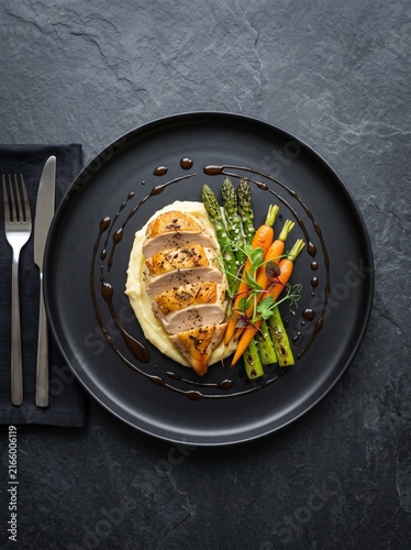 Roasted chicken breast served with mashed potatoes and glazed carrots.