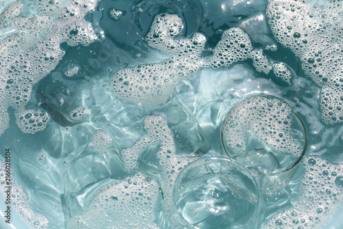 Fotografie Glass cups soaking in soapy water with white foam