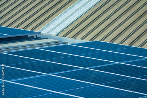 Bild auf Leinwand A solar installation engineer in a white helmet and high visibility vest precisely walks the dim panel ridge as light fades over the array high on an industrial warehouse roof in a Thai