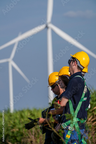 Cuadro en lienzo An engineer pair on the move shoulder their gear along the field margin on the margins of the wind farm fields in softening afternoon light at a renewable energy site in Thailand