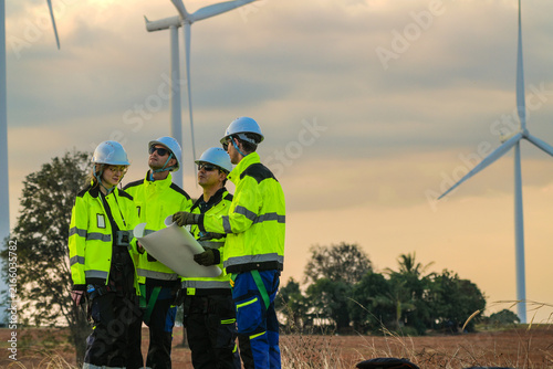 The wind farm crew of four stop while the leader points out tomorrow's machines on the park road under fading skies in pink pastel dusk deep inside a tropical wind energy park image 6465.