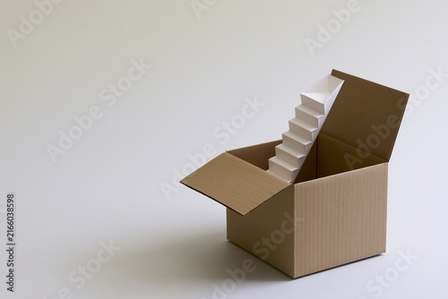Open box with a paper staircase rising surreal concept