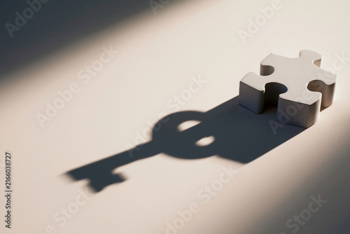 Puzzle piece casting a key shaped shadow surreal solution concept