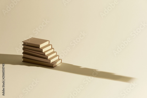 Stack of books casting a staircase shaped shadow surreal concept